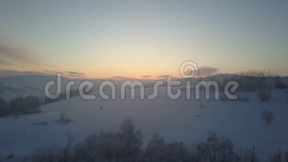 日出时空中北欧冬季景观飞越雪山森林冬季无人驾驶飞机在雾中飞过山丘视频的预览图