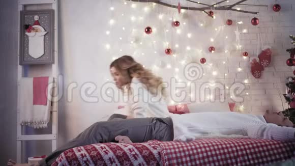 一个年轻的女人在靠近圣诞树的卧室里给一个男人一份圣诞礼物他穿着圣诞手套视频的预览图