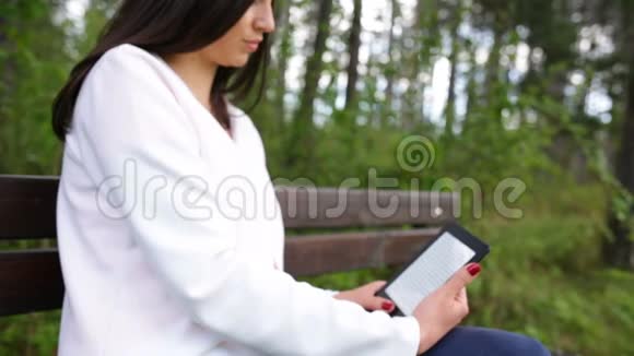 有魅力的年轻女性公园里有电子书平板电脑滑动滑块视频的预览图