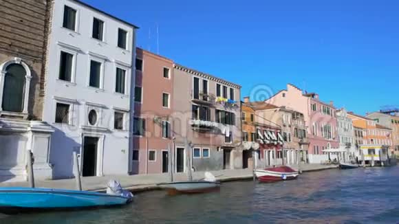 在威尼斯的运河上航行的船可以看到博拉诺舒适的多彩房子视频的预览图