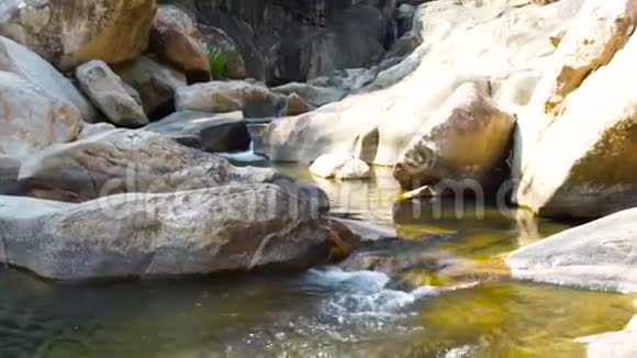 干净的水流在山岩河附近来自热带瀑布的湍急的水流倾泻在山上视频的预览图
