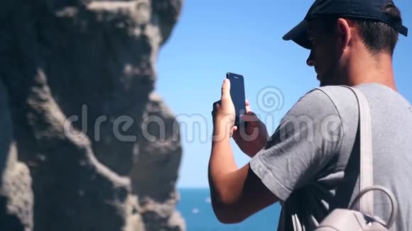 一个戴着帽子的游客拍了一张靠近大海的美丽悬崖的照片高清1920x1080慢动作视频的预览图