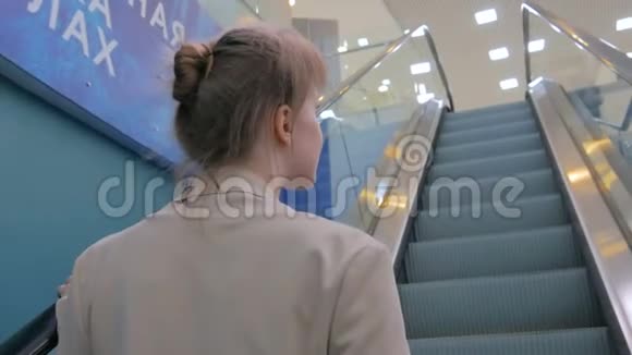 一位年轻女子在自动扶梯上走动在商场里四处张望视频的预览图