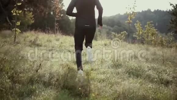 慢动作人在秋草山上奔跑相机跟随越野跑者享受大气坠落的自然视频的预览图