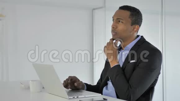 美国黑人商人在笔记本电脑上的思考和工作视频的预览图