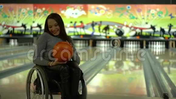 有魅力的残疾女孩坐在轮椅上玩保龄球用保龄球跳舞视频的预览图