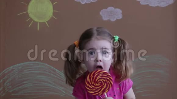情感女孩的肖像与大糖棒棒糖孩子吃糖果带着棒棒糖的漂亮小女孩视频的预览图