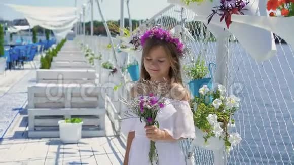可爱的小女孩的肖像手里拿着野花在海湾酒吧4K视频的预览图