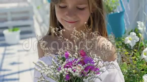 可爱的小女孩的肖像手里拿着野花看着镜头4K视频的预览图