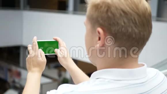 这家伙在智能手机上玩射击和比赛绿色手机屏幕键控一个男人视频的预览图