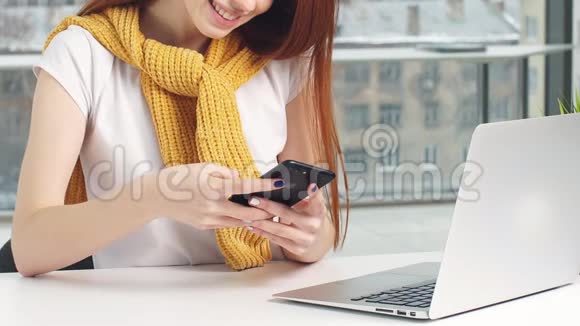 漂亮的红发女孩在办公室工作使用笔记本电脑和手机视频的预览图