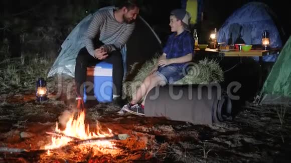 在露营地到森林的幸福家庭肖像父亲和孩子在篝火旁玩到林地旅行营地视频的预览图