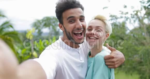 情侣拍照拥抱欢笑走出热带森林男男女女开心笑谈视频的预览图