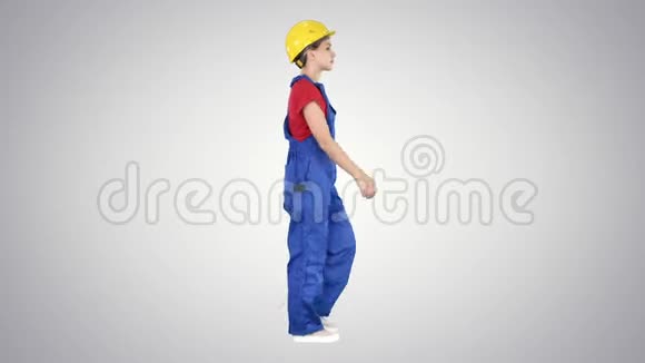 年轻的女建筑工人在黄色硬帽行走在梯度背景视频的预览图