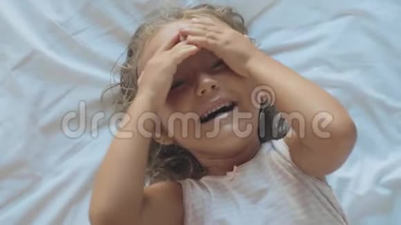 可爱的童女躺在床上看着相机笑着的肖像视频的预览图