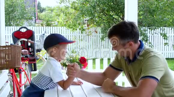 爸爸和他四岁的儿子一起玩摔跤他们玩得很开心在夏天在花园里视频的预览图