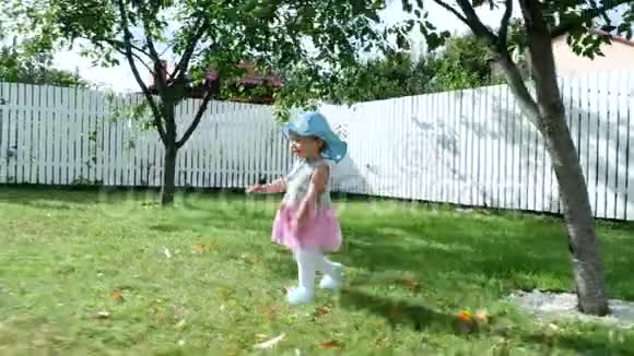 一个漂亮的一岁女孩戴着一顶太阳帽和一件华丽的裙子静静地走向她的母亲妈妈带着孩子视频的预览图