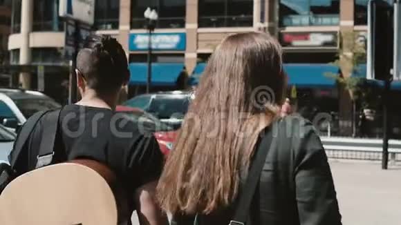 年轻漂亮的夫妇一起在市中心散步芝加哥美国男人拿着吉他女人拿着素描盒视频的预览图