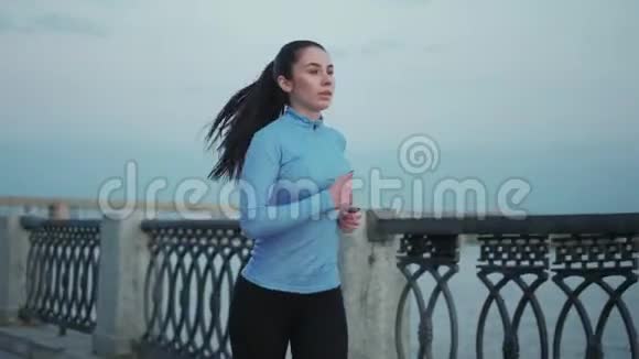 清晨小女孩沿着荒芜的堤岸慢跑美丽的女运动员在户外锻炼视频的预览图