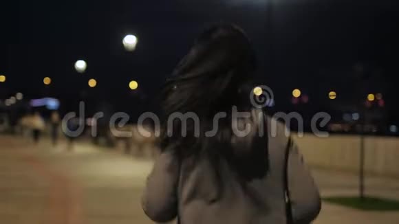 女孩穿过夜城用耳机听音乐户外运动夜夜跑视频的预览图