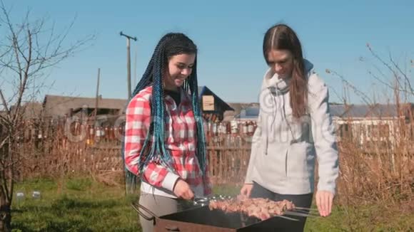 两个女朋友在后院的木炭烤架上做什什利克肉一起聊天和微笑视频的预览图