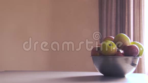 桌子的右边有一个装有苹果的金属碗阳光从窗户落下来视频的预览图