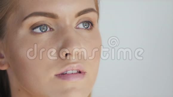 化妆师将明亮的底色眼影或色调涂在模特上并在背景上拿着眼影的外壳视频的预览图