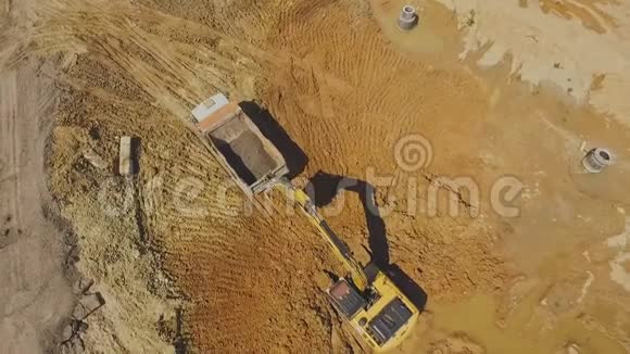 在交通交汇处施工时挖掘机将地面装载到卡车上空中射击视频的预览图