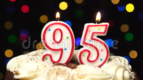 95号在蛋糕上面95号生日蜡烛燃烧在最后吹灭彩色模糊背景视频的预览图