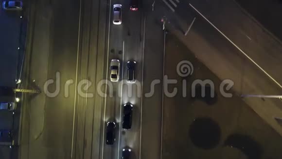 这辆车在城市十字路口灯光小径交通录像顶部向下空中无人机观看夜间有汽车的道路视频的预览图