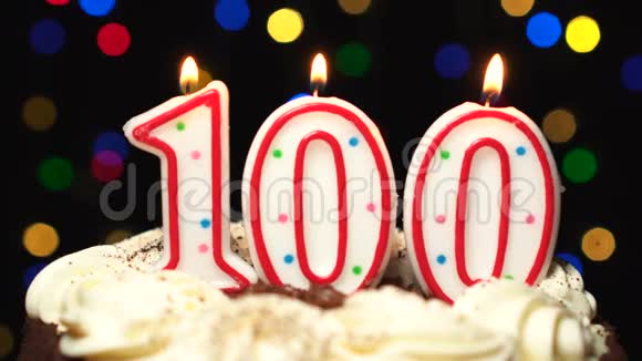 在蛋糕上面的100号一百个生日蜡烛燃烧在最后吹出来彩色模糊背景视频的预览图