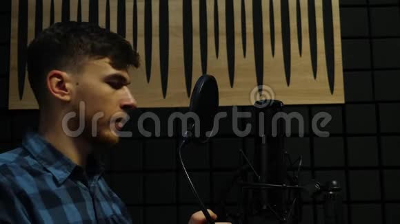 音乐家戴着耳机在录音室对着麦克风唱歌在家录音室录制这首歌的专业男歌手视频的预览图