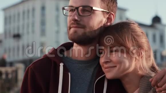 站在市中心看一边的年轻漂亮夫妇的肖像快乐的男人和女人拥抱日落视频的预览图