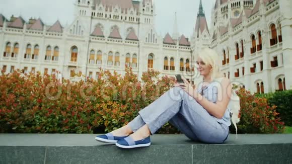 这位女士坐在匈牙利议会的背景上使用智能手机欧洲旅游业宏伟的布达佩斯视频的预览图