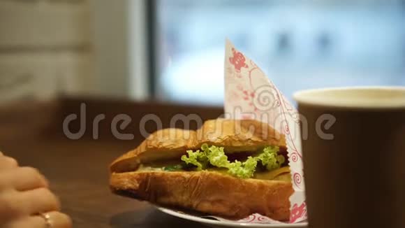 一位年轻女士正在咖啡馆里享用法式早餐咖啡和牛角面包视频的预览图
