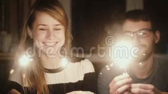 慢动作年轻的幸福夫妇晚上坐在家里拿着火花一起享受时光视频的预览图