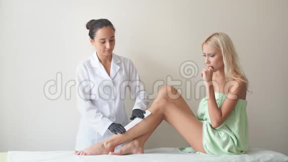 女性腿部和脱毛与热蜡疼痛程序在美容沙龙做脱毛的女人蜡脱毛视频的预览图
