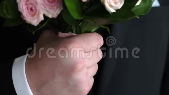 穿着深色西装和白色衬衫的男人手中捧着一束多色玫瑰特写视频的预览图