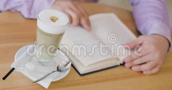 男人正在看一本书坐在咖啡馆里喝杯卡布奇诺视频的预览图