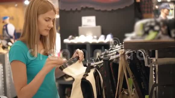 年轻漂亮的女人在商店里挑选包在商场购物销售时间消费主义概念视频的预览图