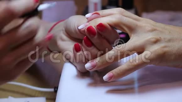 修指甲后涂粉白色指甲油特写女性指甲画用画笔创建梯度视频的预览图