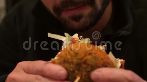 年轻的留着胡子的高加索时髦男人吃纯素豆腐汉堡4K慢行视频的预览图