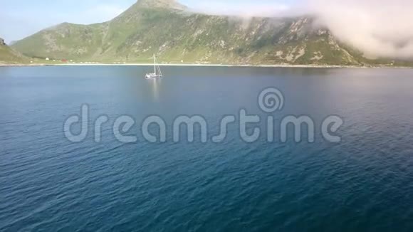 从空中俯瞰漂浮在海中的游艇和多云的山脉视频的预览图