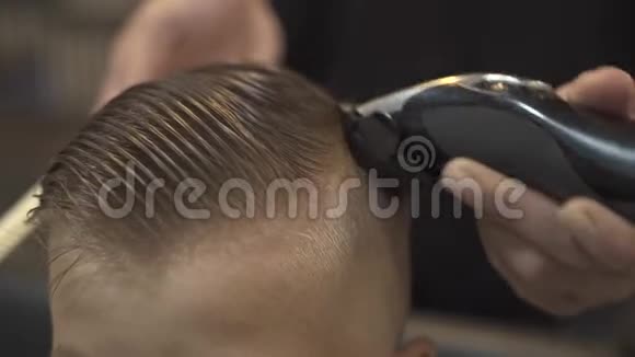 儿童理发师用理发机把小男孩剪得很近有电器的儿童发型视频的预览图