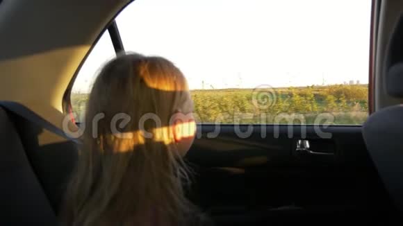 年轻的白种人女孩坐车慢动作聚焦到车外窗外田野和农村的场景秋日日落视频的预览图