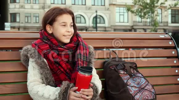 一个小女孩坐在大城市的长凳上视频的预览图