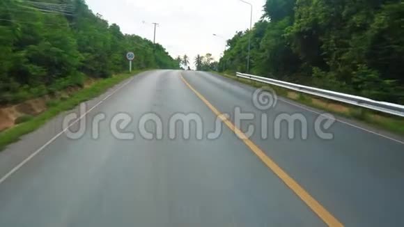 沿着柏油路在森林里旅行沿着道路的树木视频的预览图