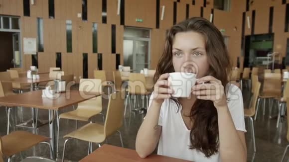 一位美丽的年轻女子在窗外喝着热咖啡做梦视频的预览图