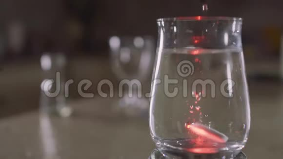泡腾片落入一个装有水和闪闪发光的彩色灯光的玻璃中视频的预览图