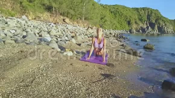 波式卵石沙滩瑜伽体式金发女郎视频的预览图